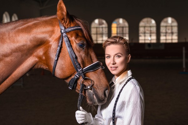 Portrait of a stylish woman hugging a thoroughbred horse. Love and care concept.