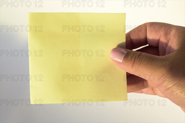 Woman's hand with painted nails holding blank letter paper on pure white background