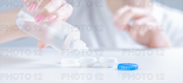 Woman pours liquid for lenses into special boxes. Ophthalmology concept.