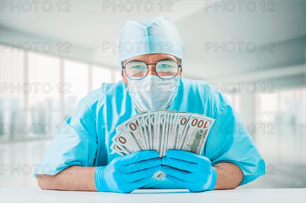 Portrait of a doctor holding hundred dollar bills. He is looking at the camera and smiling. The concept of corruption in medicine.
