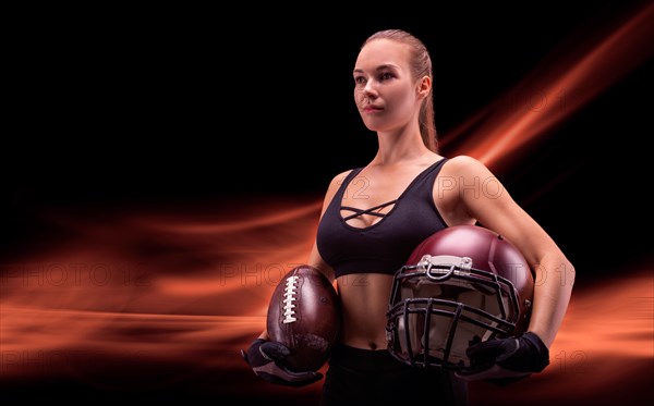 Portrait of a sportive girl in the uniform of an American football team player. Sports concept. Futuristic background.