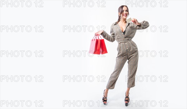 Charming brunette posing in the studio with red packages and a bank card. Gift concept. Shopping before the holidays. White background.