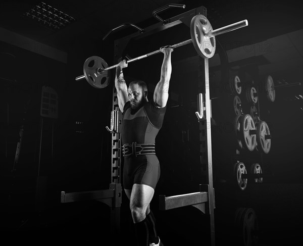 The weightlifter raises the barbell above his head and fixes the weight