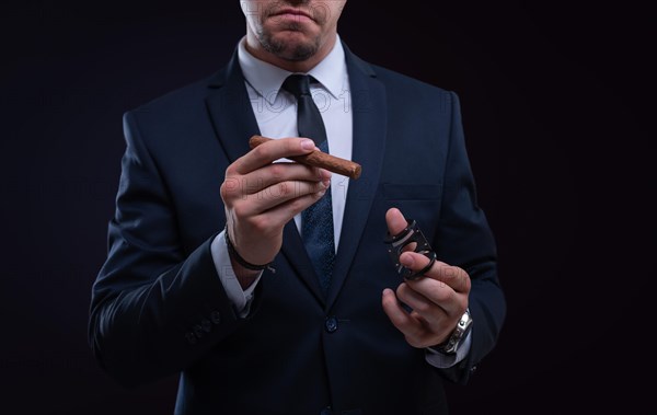 Image of an adult stylish man in a suit with a cigar. Cigar clubs concept.