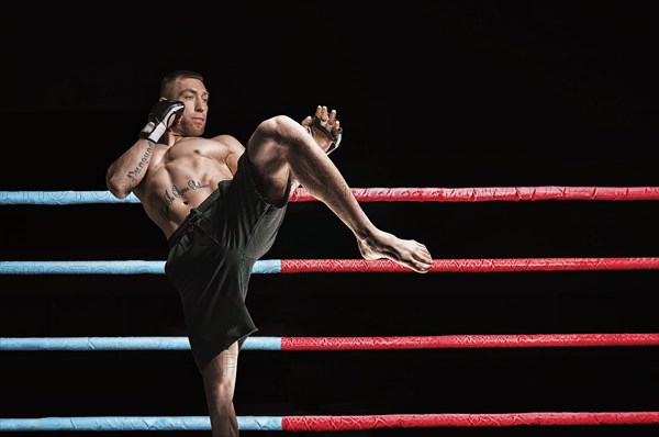 Thai boxer in the ring hits with a knee. The concept of sports