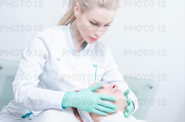 Doctor in a dressing gown examines the patient's face. Plastic surgery concept.