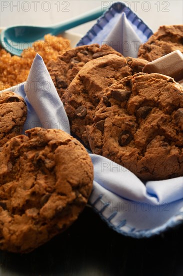Chocolate chunk cookies on a blue napkin with a rustic wooden backdrop