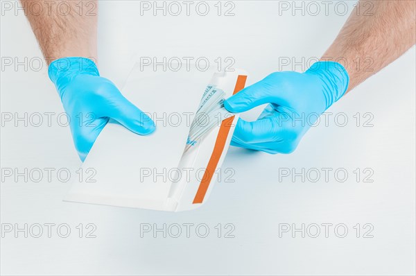Image of hands in medical gloves holding an envelope with dollars. The concept of corruption in medicine.