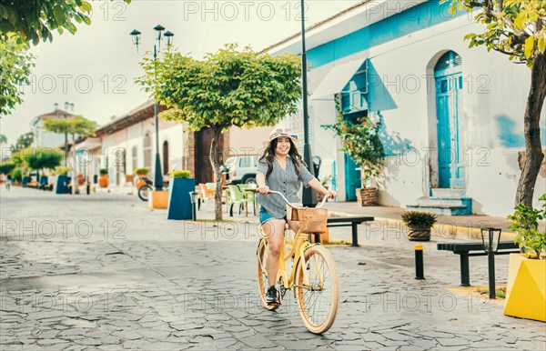 Beautiful and happy girl riding a bicycle on the street of La Calzada