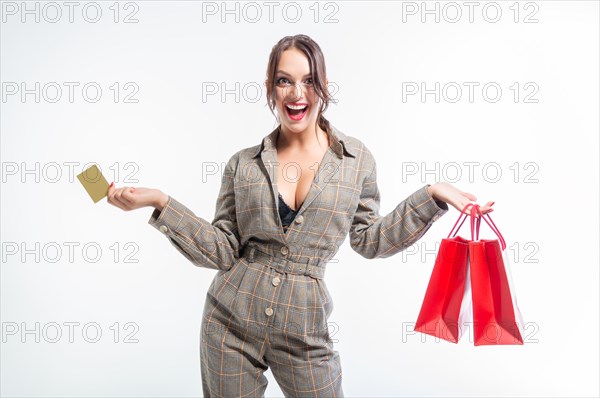 Charming brunette posing in the studio with red packages and a bank card. Gift concept. Shopping before the holidays. White background.