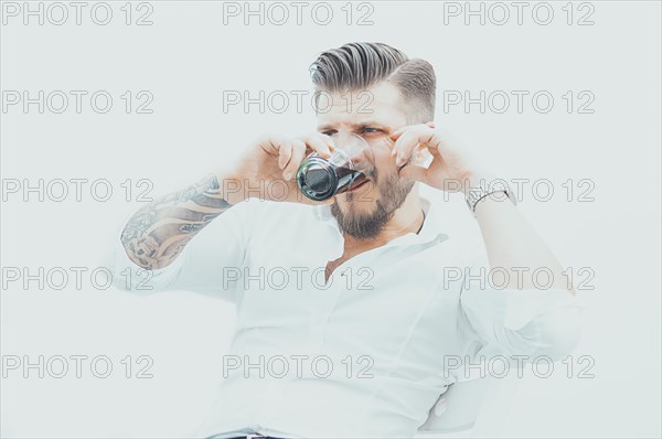 Stylish man sits on a chair and gets drunk with rum and cola. The concept of unsuccessful business