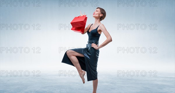 Stylish adult tall woman posing in studio with gift bags. Shopping concept. Shopping centers.