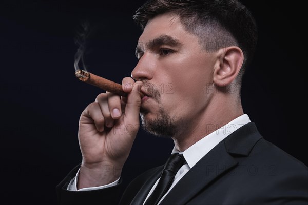 Portrait of a stylish man in a suit with a cigar. Business concept.