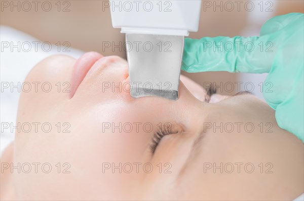 Young pretty woman receiving treatments in beauty salons. Ultrasonic cleaning procedure. Hardware cosmetology.