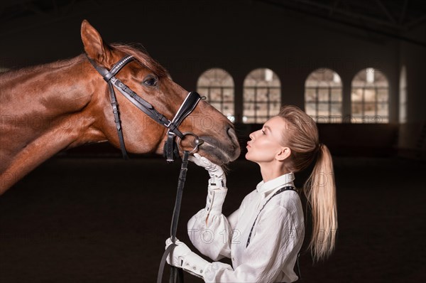 Portrait of a stylish woman hugging a thoroughbred horse. Love and care concept.