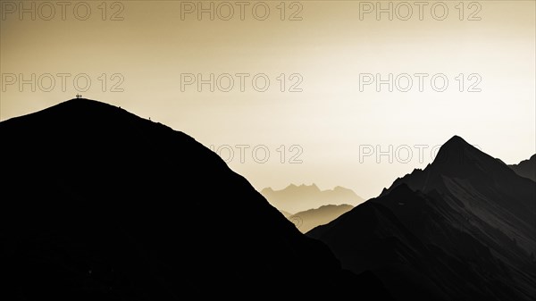 Mountain ridge with mountaineers and Swiss mountains and Lake Thun in the background at sunrise