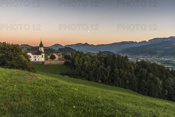 Church in the hamlet of Schlatt with a view of the Alpstein mountains with Hoher Kasten and the village of Appenzell at dusk