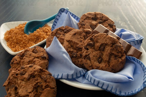 Chocolate chip cookies on a plate with brown sugar on the side