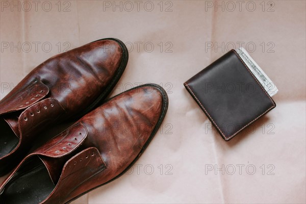 Brown men's shoes made of genuine leather and a brown leather wallet with money