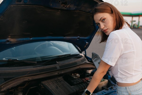 Young beautiful hot girl auto mechanic pours oil