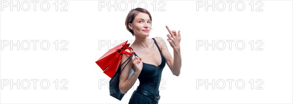 Portrait of a beautiful woman with red packages. She shows a fuck sign and smiles. Shopaholic concept. Shopping centers. Sales.