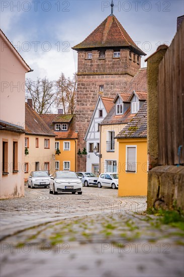 Deer e-car sharing cars with a view through an old town alley with parked cars and cobblestones