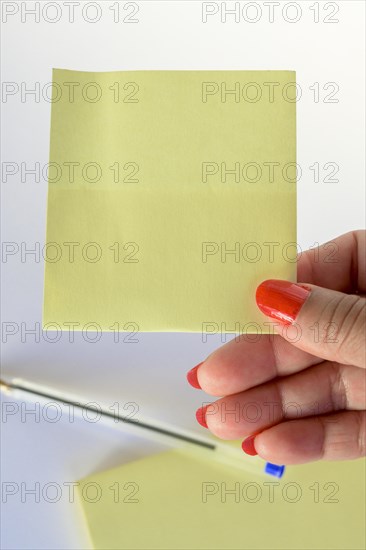 Woman's hand with painted nails holding blank letter paper on pure white background