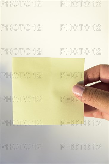 Woman's hand with painted nails holding blank letter paper on pure white background
