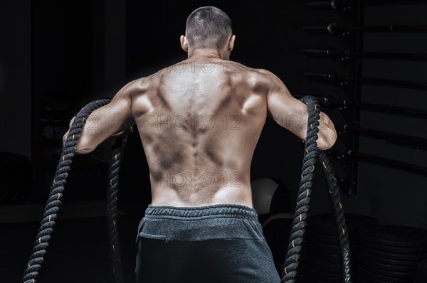 Portrait of an athlete who pulls the ropes. Back view. The concept of sport and healthy lifestyle.