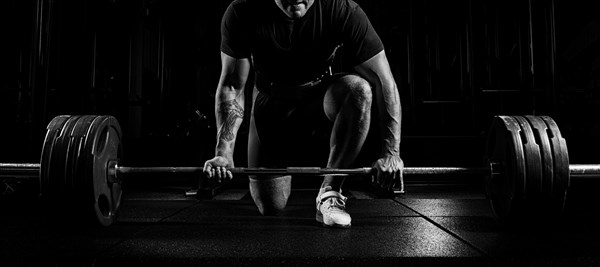 Professional athlete bent over the barbell and is preparing to lift a very heavy weight. Front view