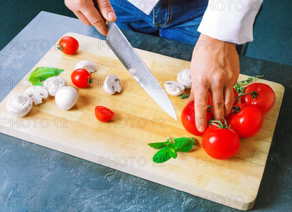 Professional chef cuts vegetables with a sharp knife from Damascus steel.