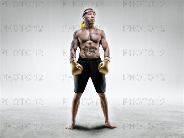 Professional wrestler is standing in a bright room. Mixed martial arts