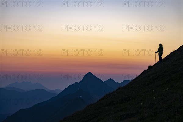 Mountaineer on mountain ridge with Rothorn peak in the background at blue hour