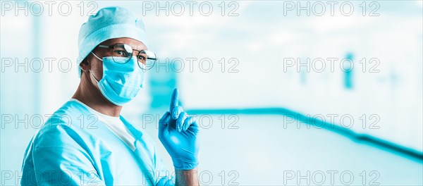 Portrait of a doctor in a hospital. He optimistically raises his finger up. The concept of new ideas in medicine.