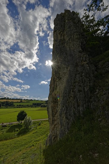 Striking limestone rock formation Burgstein with blue and white sky in the upper Altmuehltal surrounded by green vegetation