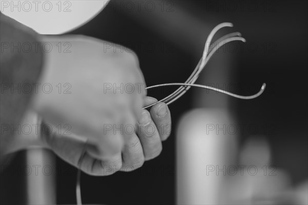 Violinmaker artisan hand in his workshop hold purfling fillet made of evony and ivory or pear wood ready to be inserted in the carved all around the shape for aesthetic touch and prevent cracking