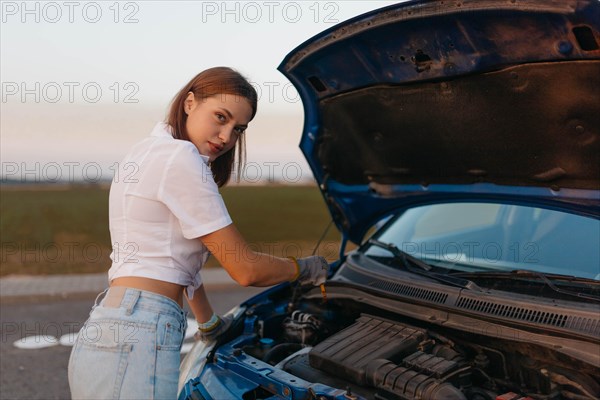 Young beautiful hot girl driver checks oil level