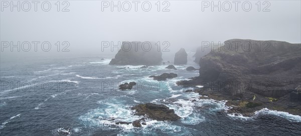 Sea stacks and sea cliffs in mist during stormy weather at Eshaness