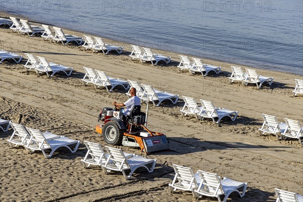 Early in the morning on the sandy beach of Kusadasi. The sunbeds are being prepared