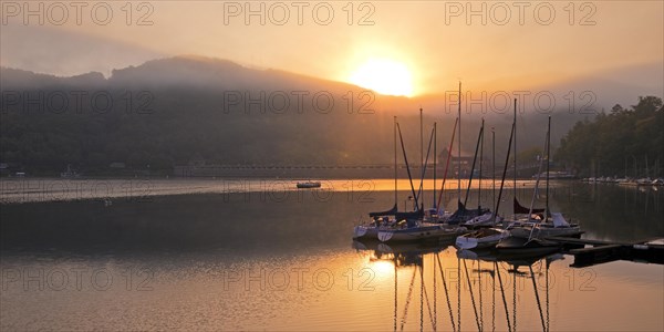 Sunrise over the Eder dam with dam wall and pleasure boats on the Edersee