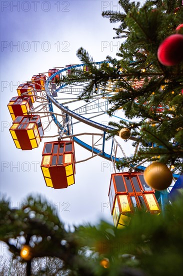 An illuminated Ferris wheel and Christmas decorations at dusk