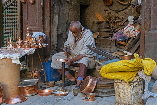 Moroccan coppersmith working in workshop on Place Seffarine