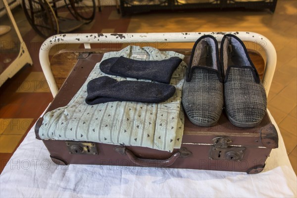 Suitcase with pyjamas and slippers of psychiatric patient on hospital bed in the Dr Guislain Museum about the history of psychiatry in the former Guislain Hospice