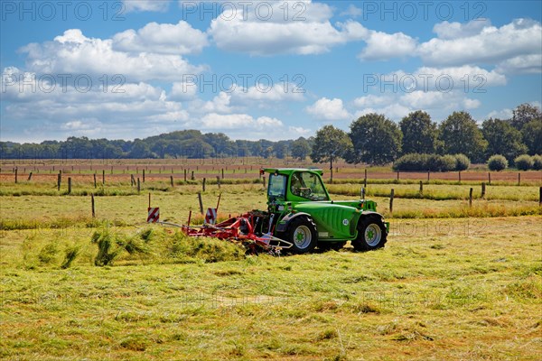 A farmer with his tractor and hay tedder