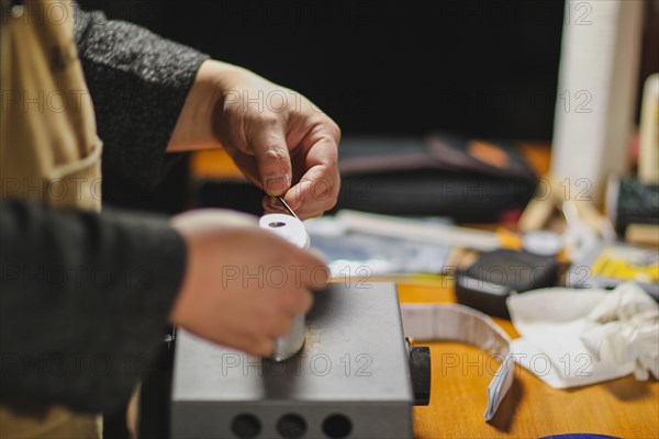 Unrecognizable luthier lute maker artisan both hands performing bend controller purfling strips process in iron tool for a new raw back and front plates of classic handmade violin in his workshop in Cremona