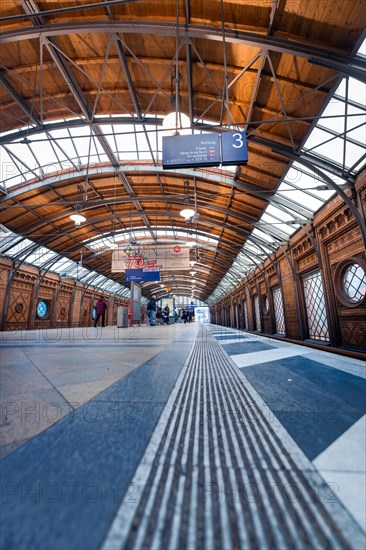 View along an empty platform under a wooden roof with tracks and scoreboard