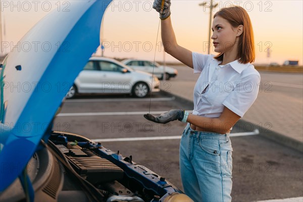 Young beautiful hot girl driver checks oil level