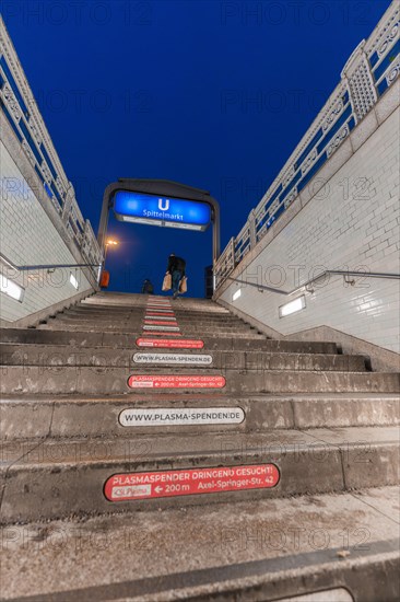 Underground entrance at night with steps and people passing by