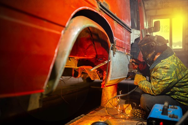 Welding work on car body repair in the garage. Truck repair