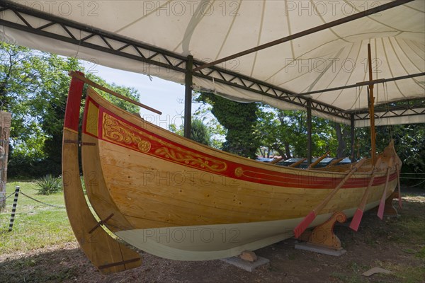 Traditional wooden boat under a white tent on a sunny day with green surroundings